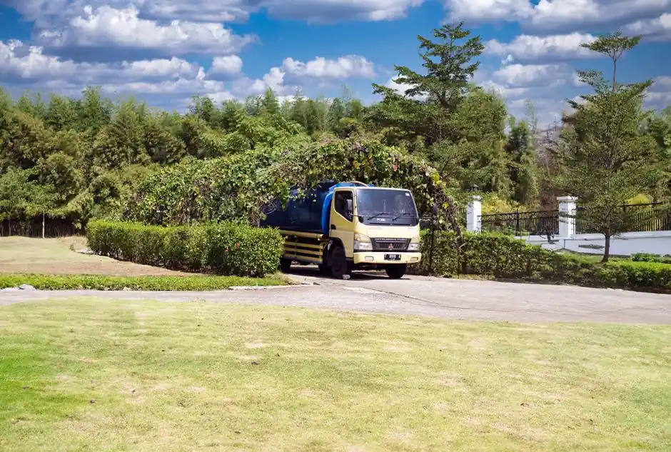 A blue truck driving through a lush, scenic countryside under a clear sky.