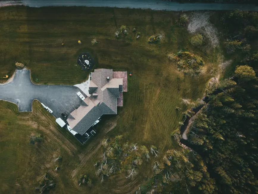 A stunning aerial shot of a suburban house surrounded by lush greenery and a driveway.