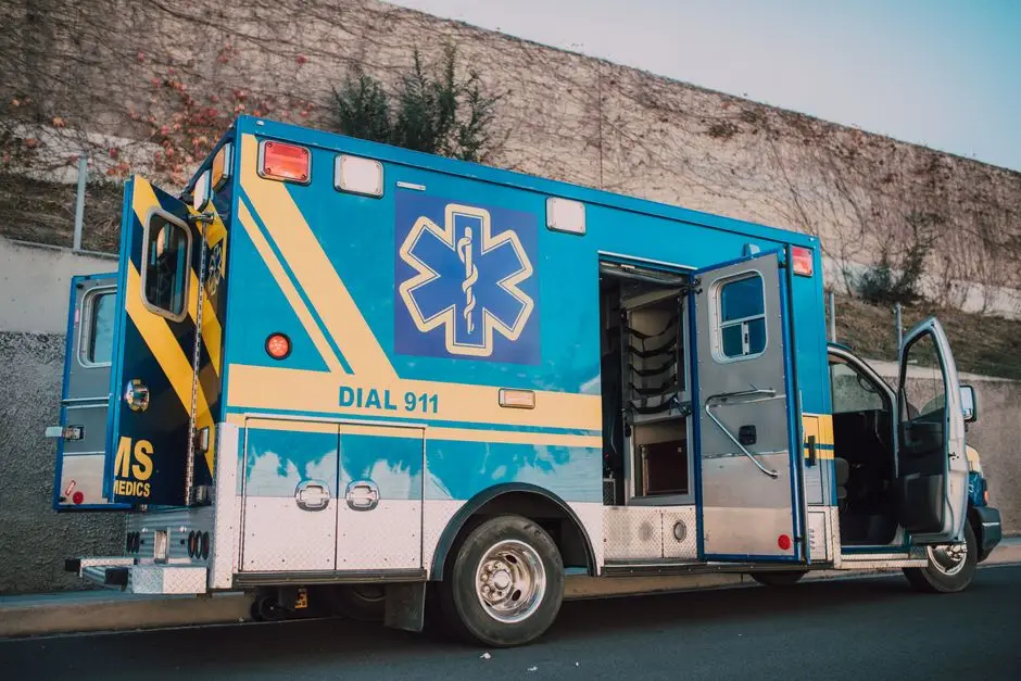 Blue ambulance parked on roadside with open doors, emergency medical service vehicle.